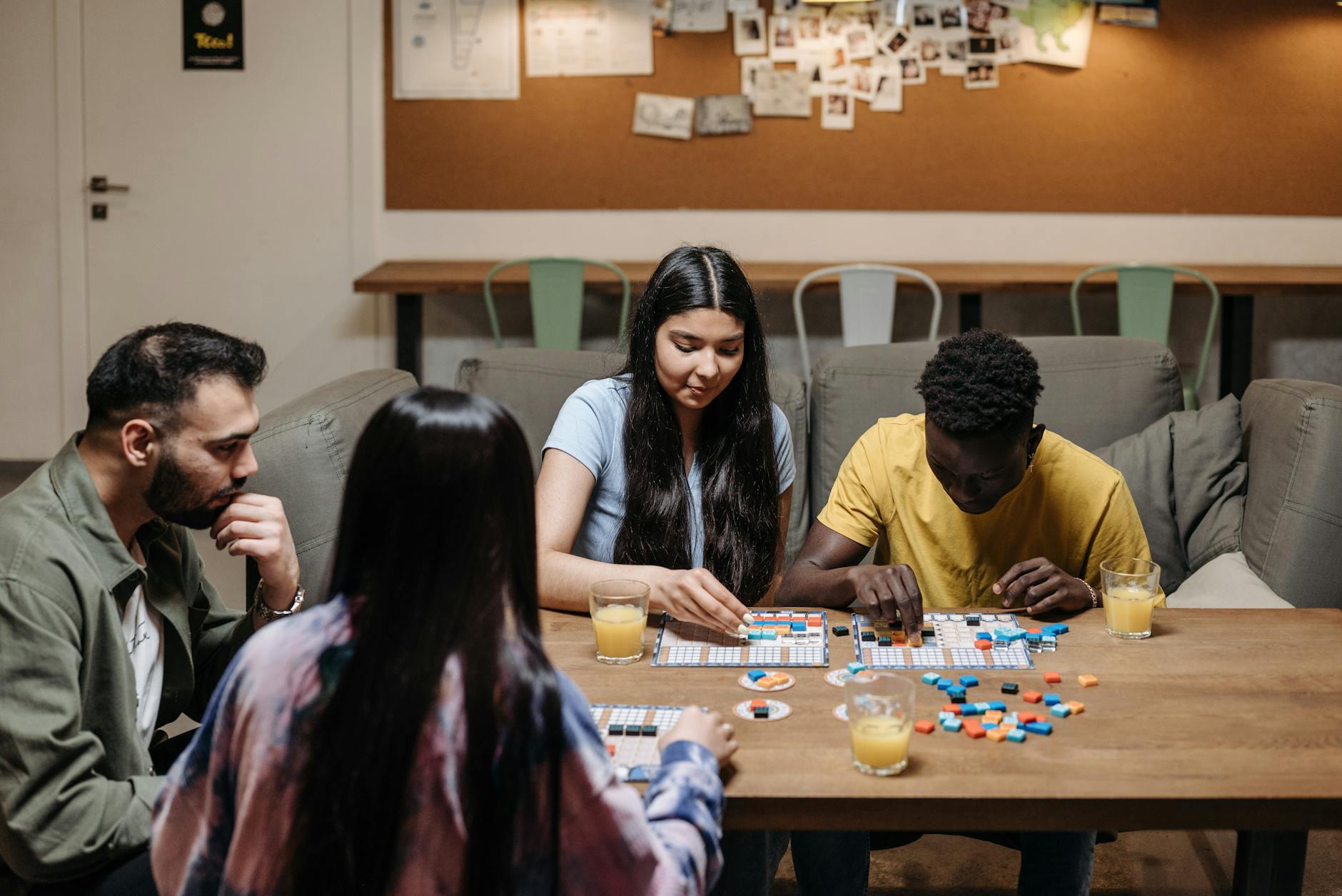 A group of people play a board game at a table.
