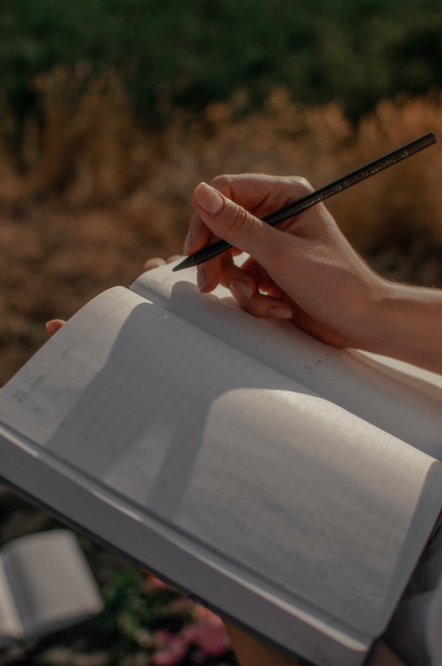 A hand writes with a pen in a journal.