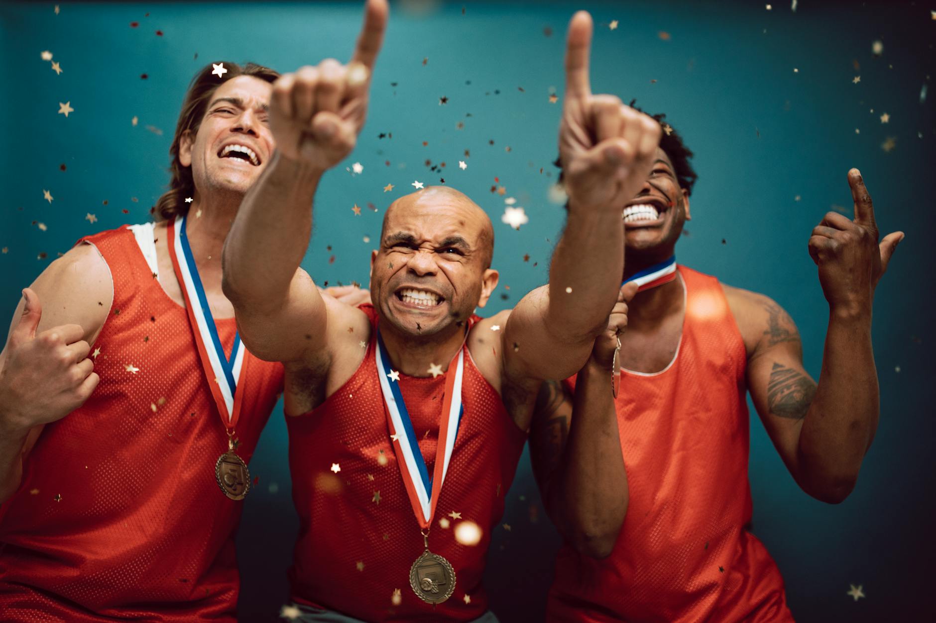 Three athletes smile and pose, and gold star confetti rains down on them.