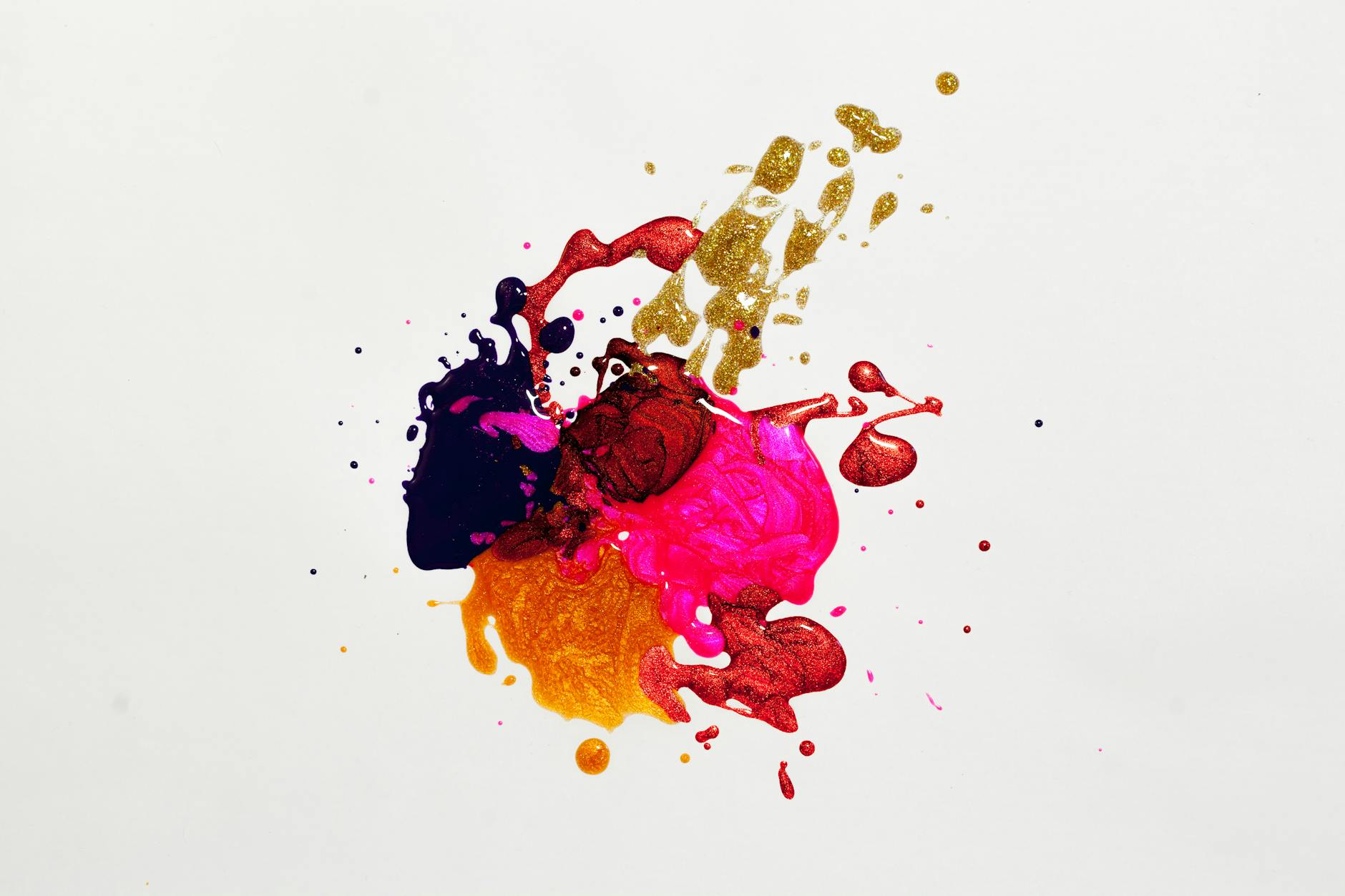 Pink, orange, burgundy, and yellow paint colors collide on a blank white canvas.
